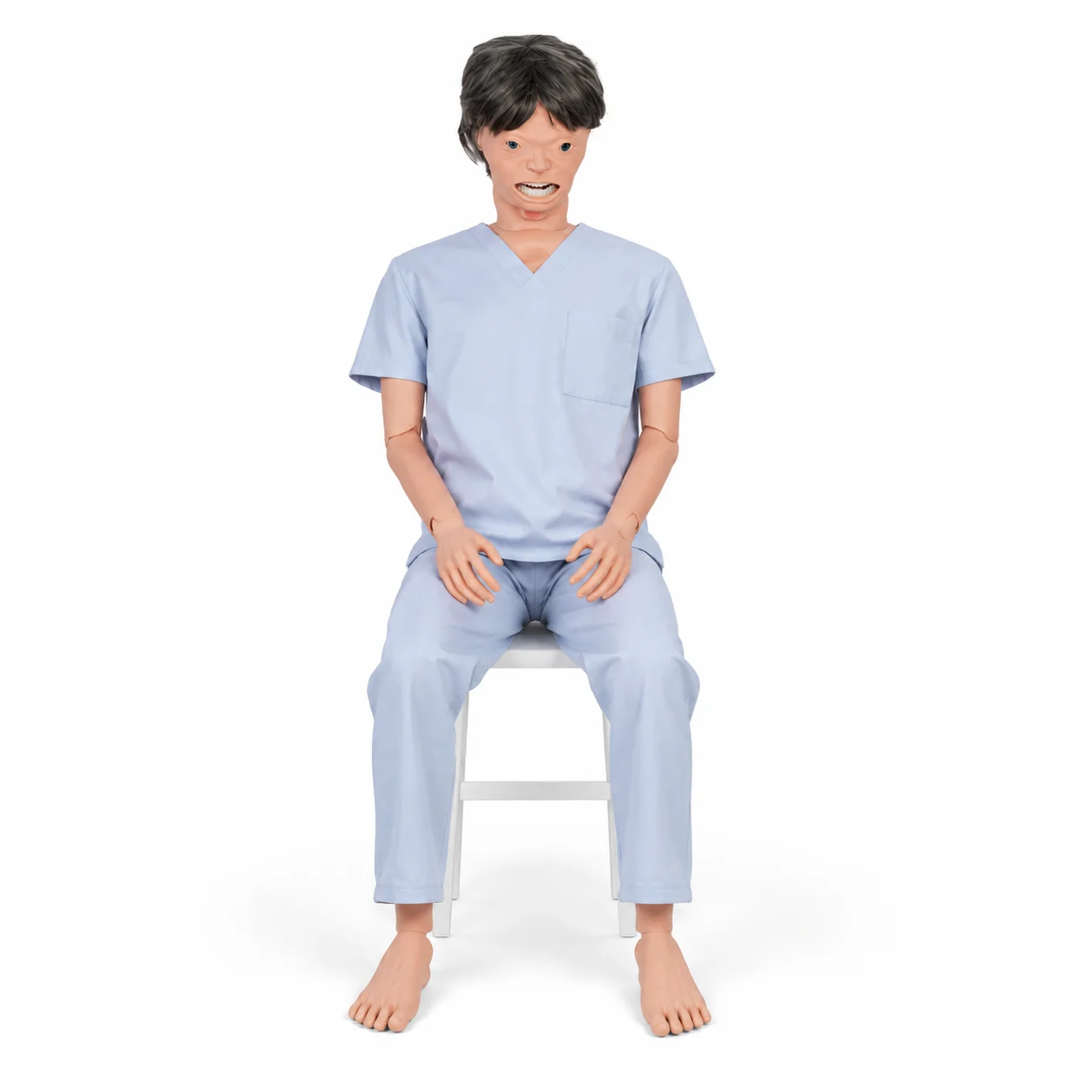 Life-size medical mannequin in light blue scrubs seated on a white chair with bare feet visible.