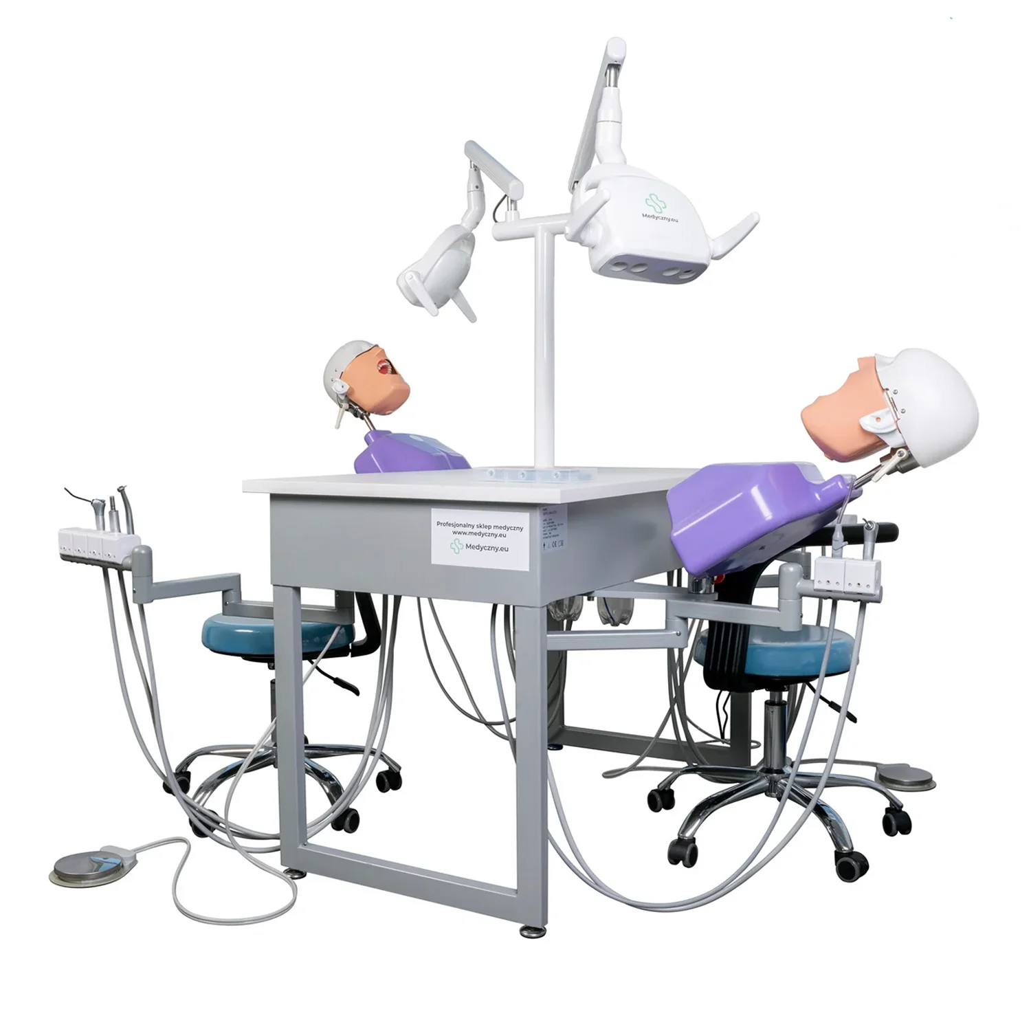 Dental training station with two patient mannequins on a dental chair and overhead light in use.