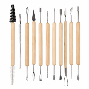 Row of wooden-handled sculpting tools with metal tips (spatulas, loops, chisels) and two brushes on the left.